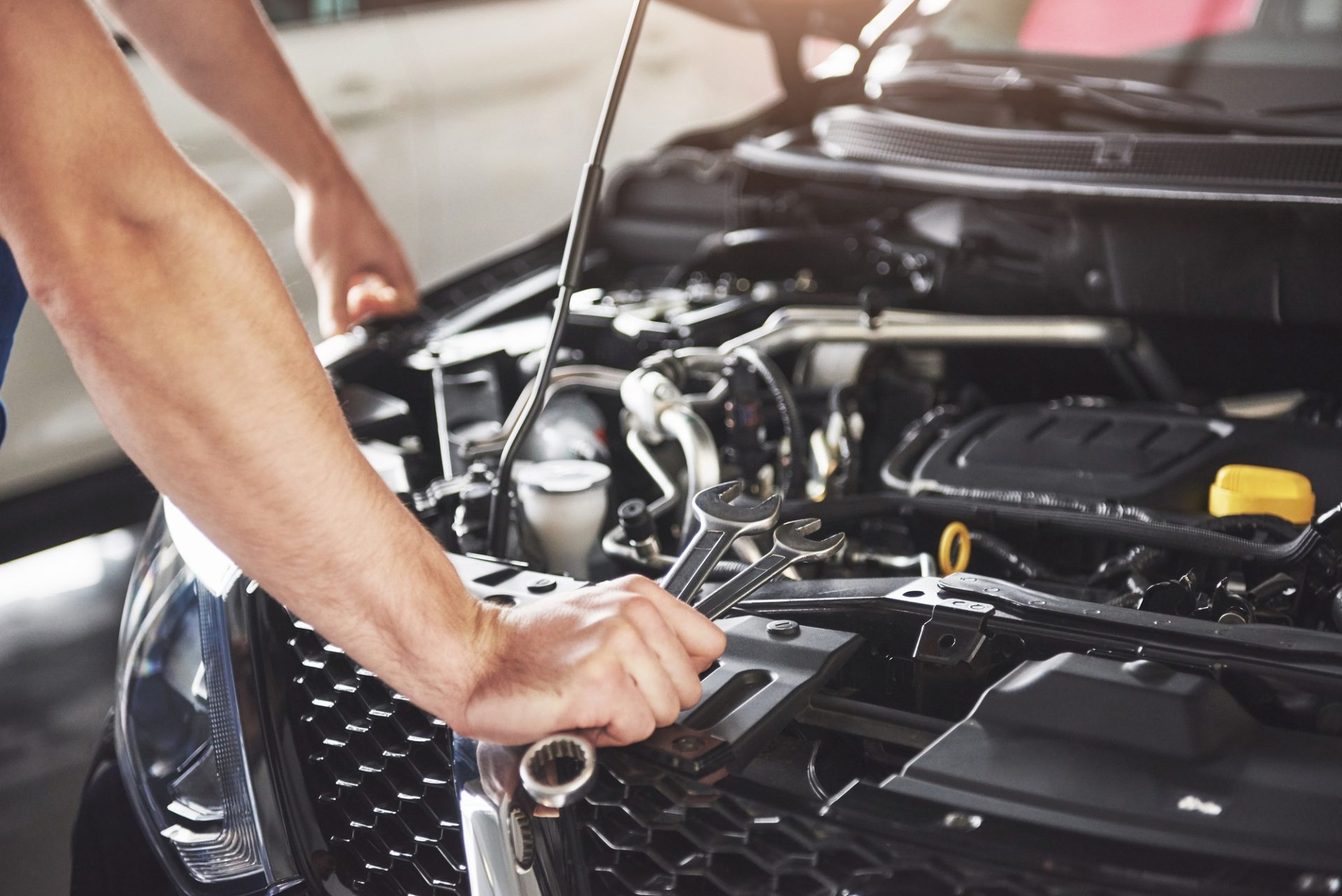 Mechanic inspecting the engine bay with tools in his hand
